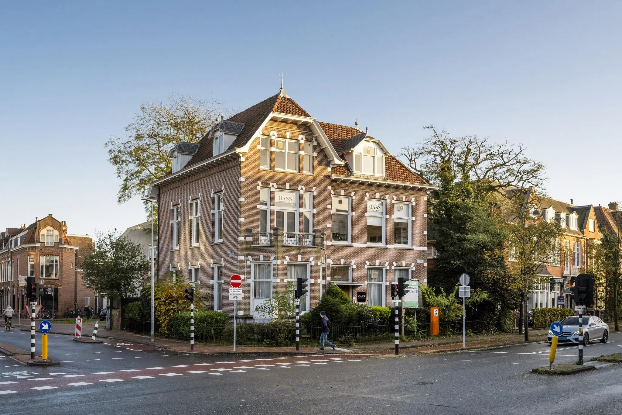 Hoekpand aan de Van Eedenstraat in klassieke bouwstijl met bakstenen gevel en wit geaccentueerde ramen, gelegen aan een kruispunt met verkeersborden en verkeerslichten.